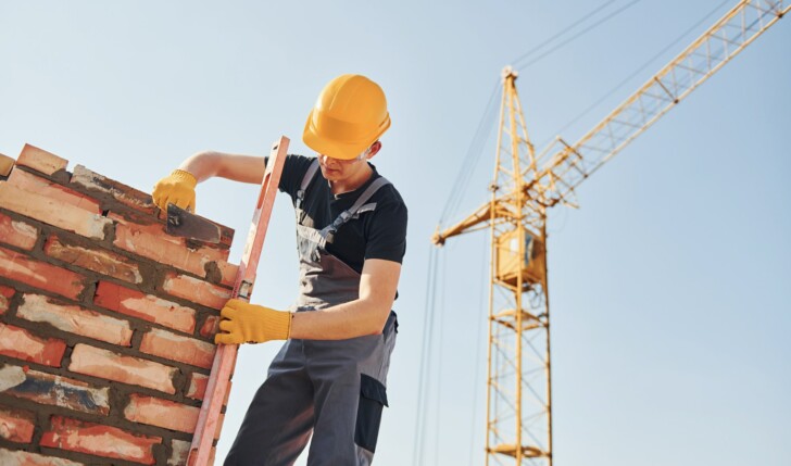 Installing brick wall. Construction worker in uniform and safety equipment have job on building