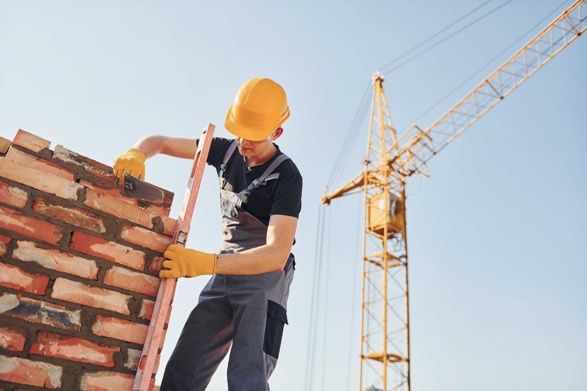Installing brick wall. Construction worker in uniform and safety equipment have job on building