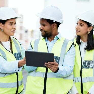 Teamwork, construction workers and digital tablet by team collaboration on building project at cons