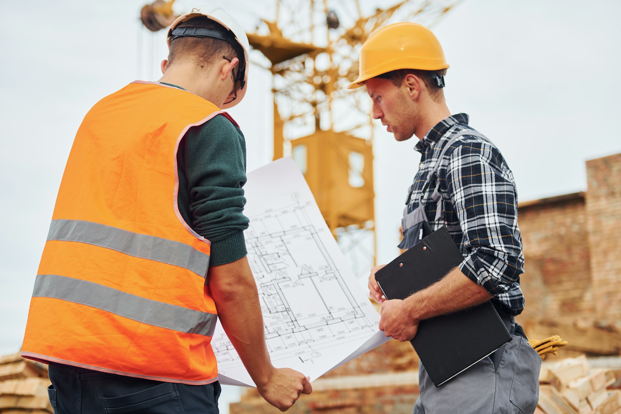 Two construction workers in uniform and safety equipment have job on building together