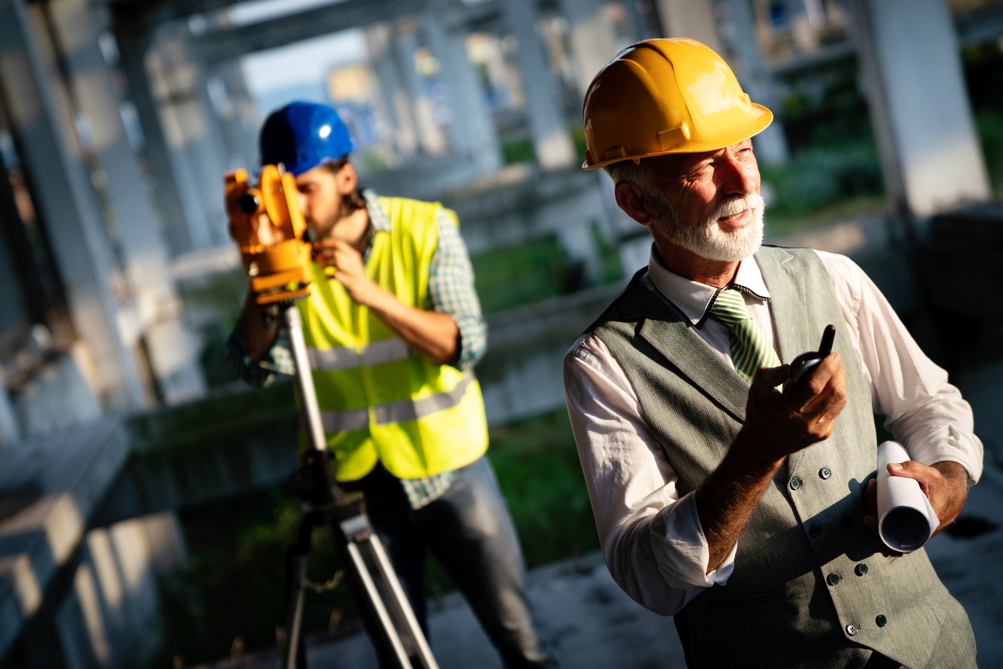 Two satisfied engineers talking at building site with construction structure in background